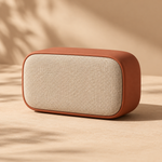 one compact portable wireless speaker in matte terracotta with woven cream fabric grille, rounded rectangular shape