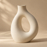 one sculptural ivory ceramic vase shaped like an asymmetric loop, tactile matte glaze