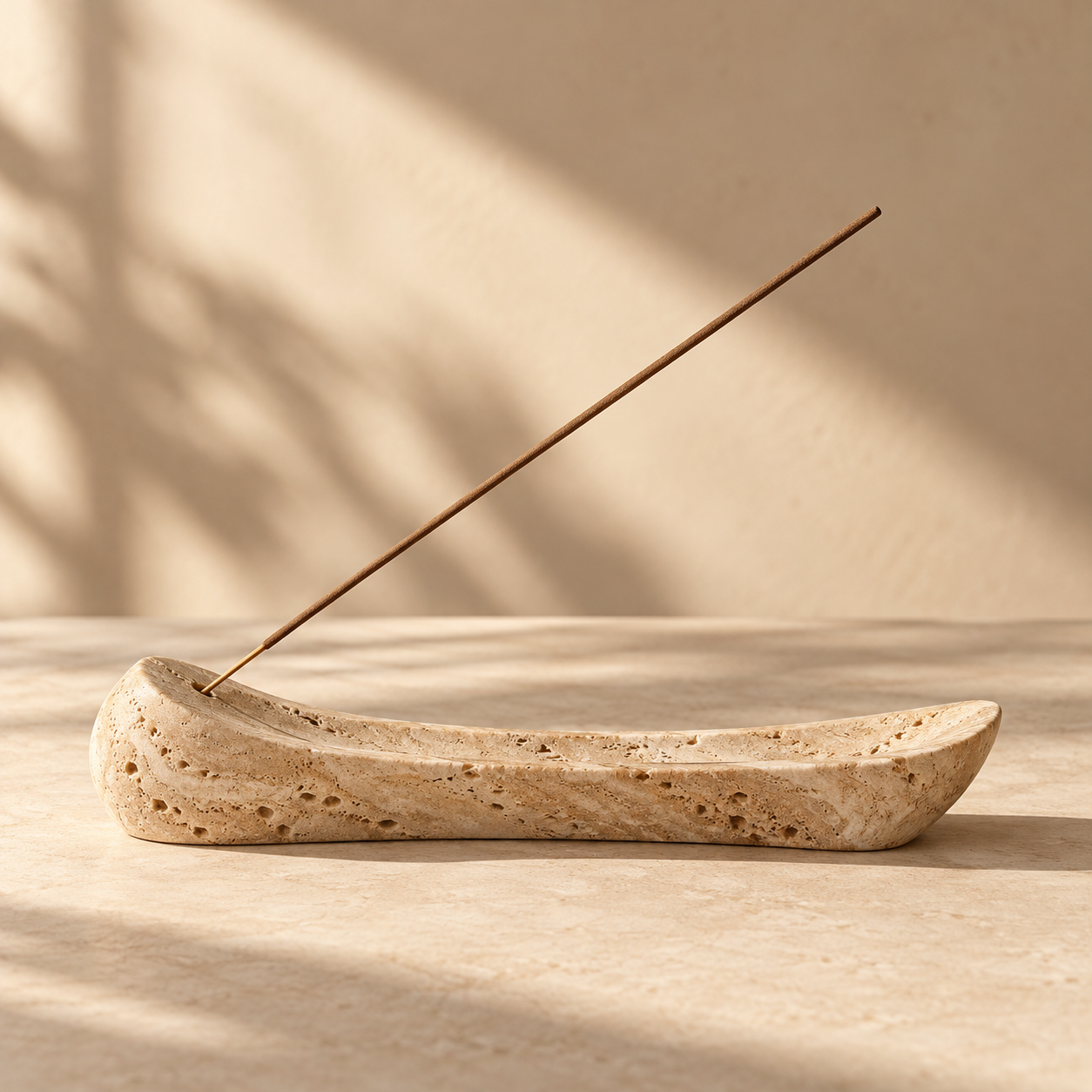 one elongated sculptural travertine incense holder with a slender unlit incense stick, delicate stone texture