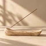 one elongated sculptural travertine incense holder with a slender unlit incense stick, delicate stone texture