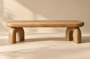 one low sculptural solid oak bench with rounded pill-shaped seat and thick arch legs, full product in wide landscape composition